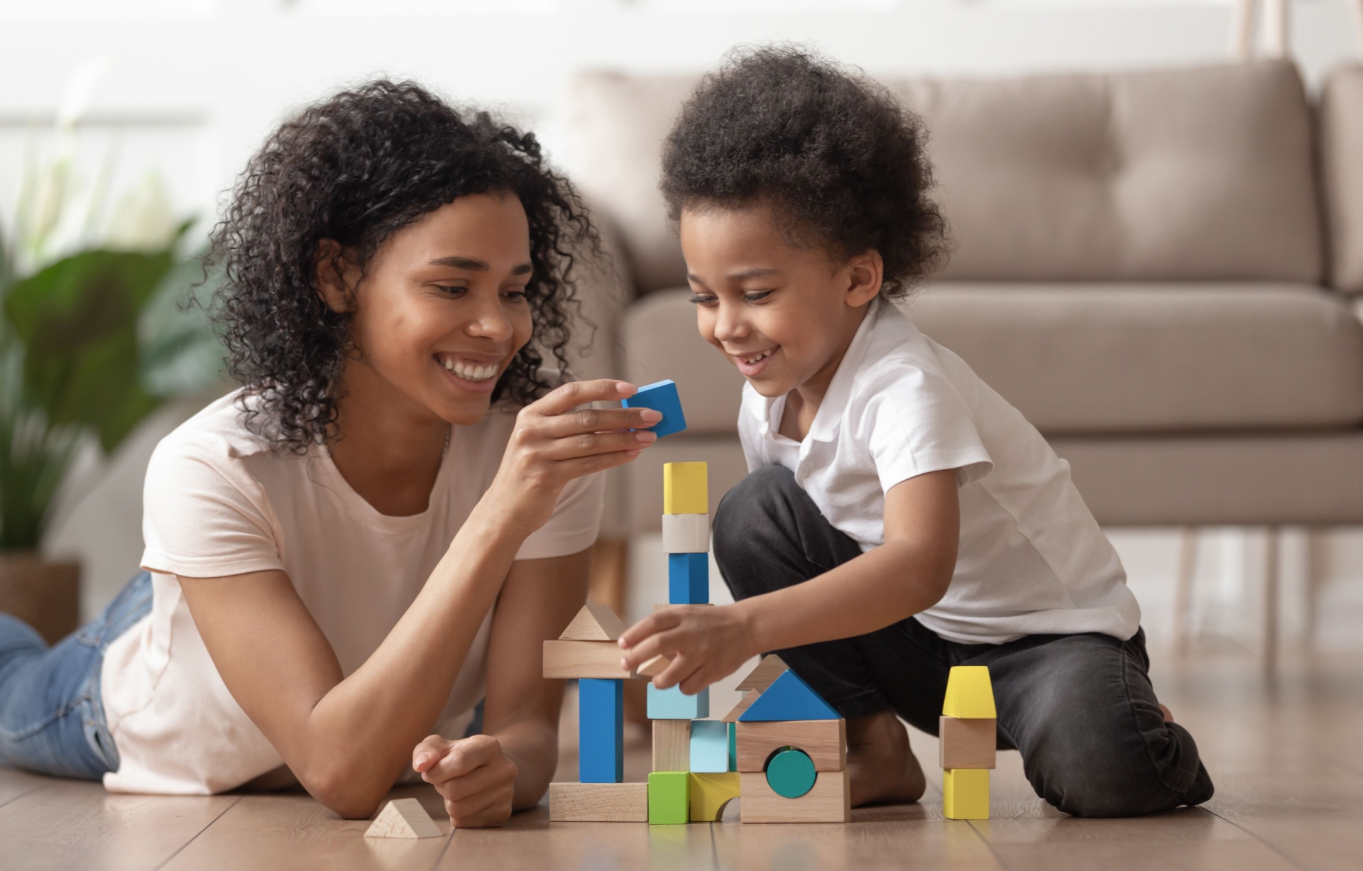 A mother and son building a tower from wooden blocks.